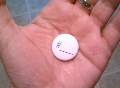 hashtag Pink button with # symbol and blank line, held in an open palm