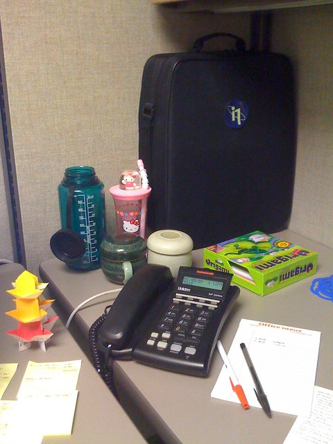A cubicle corner, showing office stationery and a desk phone. 
