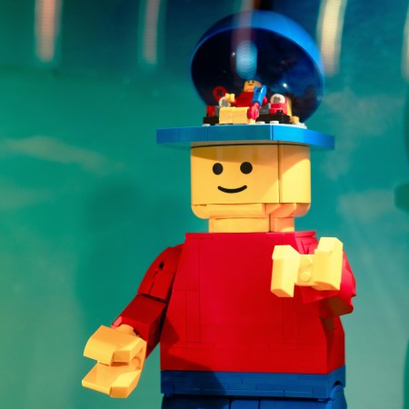 Lego minifig with red shirt and blue pants with an open head. Inside the open head is another mini-minifig , which is controlling the big minifig.