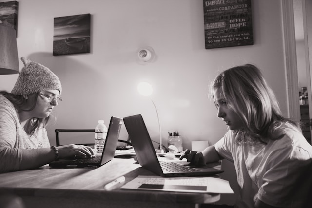 Two women writing together at a table.